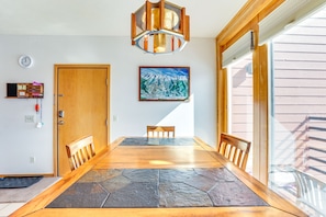 A dining area with a wooden table and chairs, a clock, a painting, and a door.