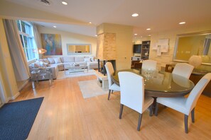 A modern living room with a dining area, a fireplace, and a large window.