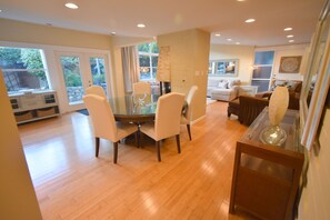 A spacious living area with a glass dining table surrounded by chairs, a fireplace, and a cozy seating area with a sofa and armchairs.