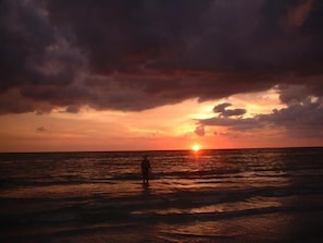 A sunset over the ocean with a person standing in the water. - Waterfront 1BR condo in Marco Island with pool, marina access, Wi-Fi, and kitchen. (Marco Island)