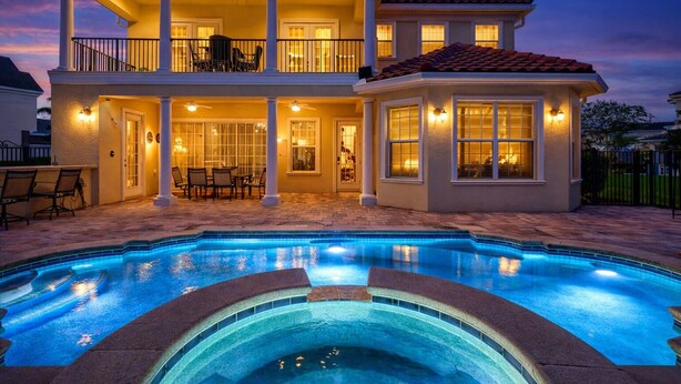 A two-story house with a swimming pool, a balcony, and a patio area with outdoor furniture. - Reunion Views | Movie Room, Amazing Views of the Tom Watson Golf Course (Kissimmee)