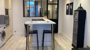 A modern kitchen with a central island, bar stools, a washing machine, and a large window.