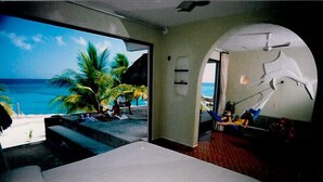 A room with a large bed, a view of a beach with palm trees, and a hammock. - Small is Beautiful. Relax ON the beach, convenient & near the Presidential Villa (Cozumel)