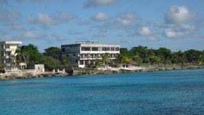 A coastal building with multiple balconies overlooking a clear blue sea. - Small is Beautiful. Relax ON the beach, convenient & near the Presidential Villa (Cozumel)