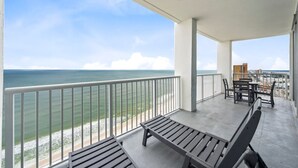 A balcony with a view of the ocean, a table with chairs, and a bench. - Island Tower 2203-3 BR | Gulf Shores (Gulf Shores)