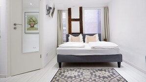 A bedroom with a bed, a door, a framed picture, a window, and a ceiling light. - Apartment Zentral (Tuebingen)