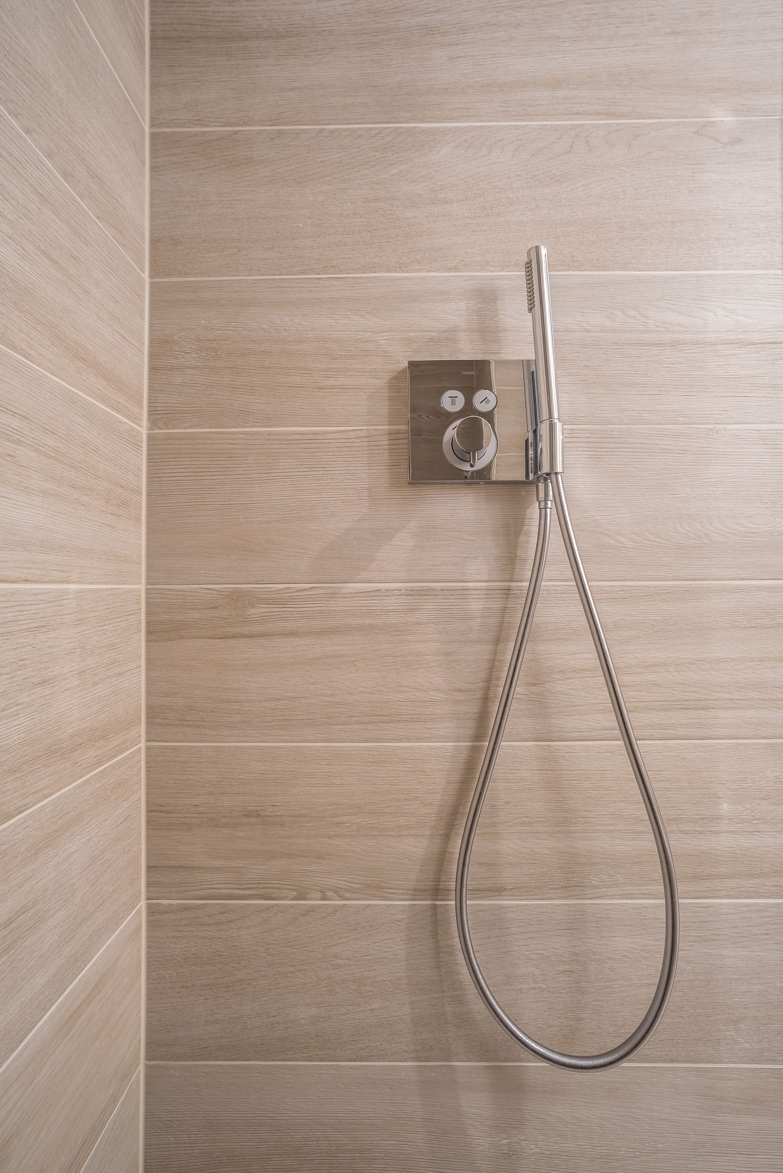 Ducha con manguera de mano y panel de control en la pared.