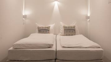 A twin room with two beds, a small bedside table, and a wall-mounted light fixture.