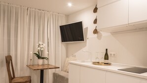A modern kitchen with a flat-screen TV, a dining table with a vase of flowers, and a wine bottle. - Apartment Zentral (Tuebingen)