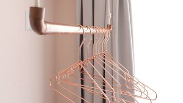 A copper wire coat rack in a room with a window and curtains.