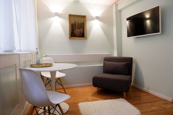 A modern room with a round table, two chairs, a grey sofa, a mounted TV, and a painting on the wall. - Apartment Zentral (Tuebingen)