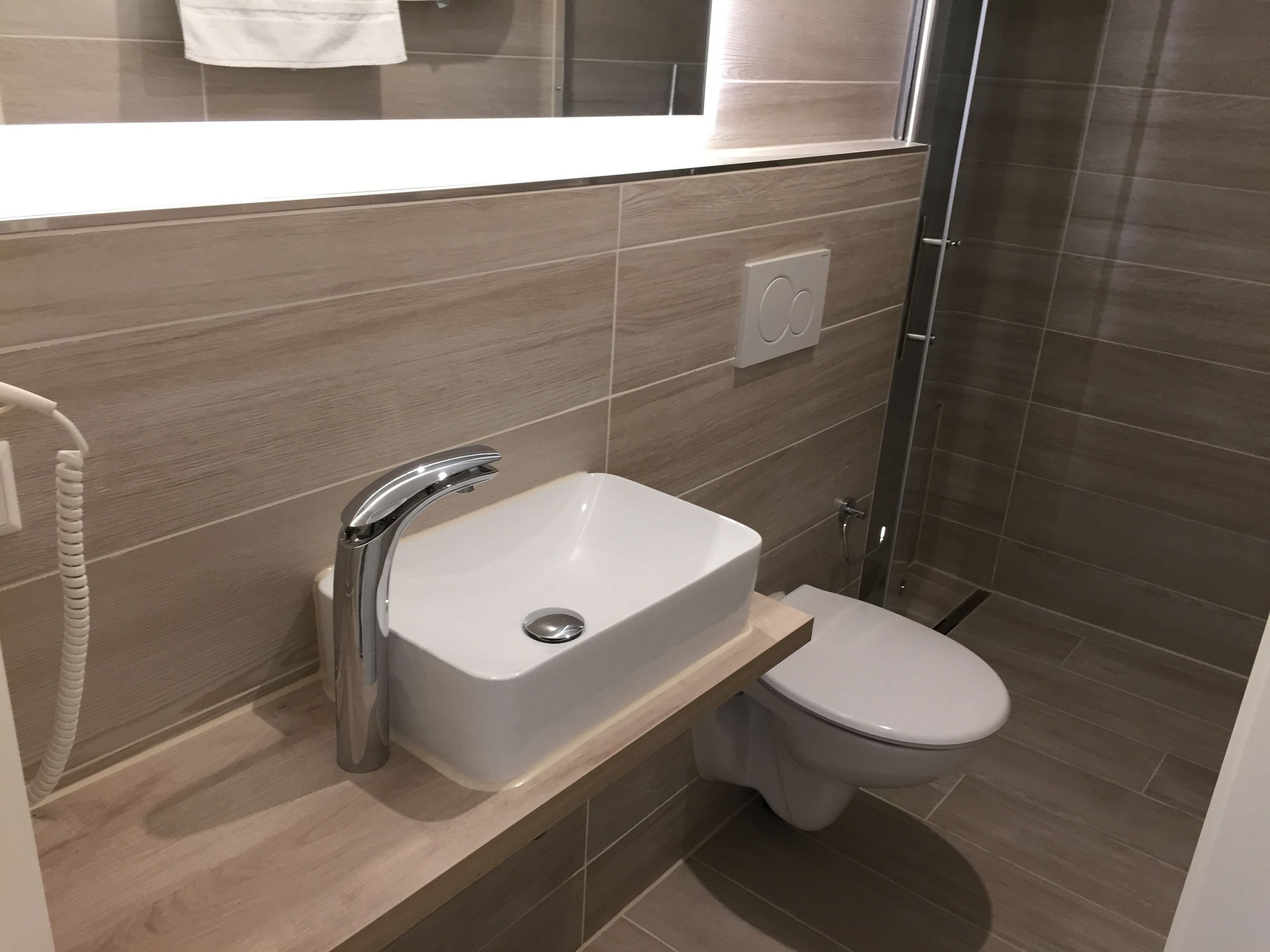 Un baño moderno con lavamanos blanco, inodoro y zona de ducha.