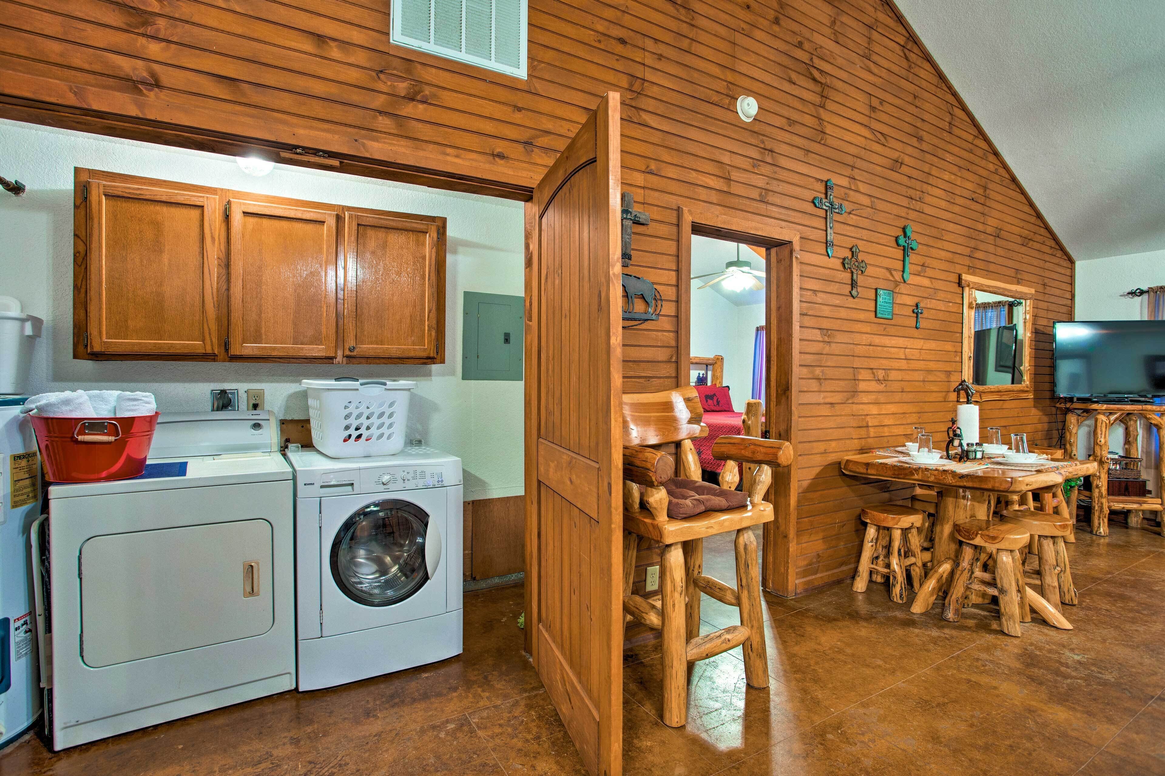 Une cuisine rustique avec des meubles de rangement en bois, un lave-linge, une table à manger avec des tabourets et un grand téléviseur.