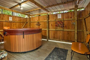 Un'area spa in legno con vasca idromassaggio, una panca di legno e una sedia.