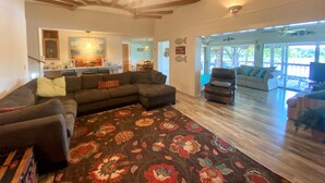 A spacious living area with a large sectional sofa, a patterned rug, and a ceiling fan.