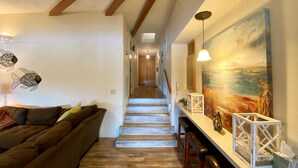 A modern interior with a wooden staircase, a living area with a sofa, and a painting on the wall.