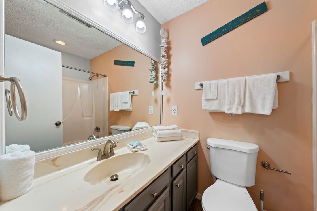 Ein Badezimmer mit Waschbecken, Spiegel, Handtuchhalter und Toilette.
