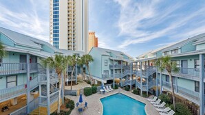 Un hotel con piscina, varios balcones y vistas a un edificio alto.