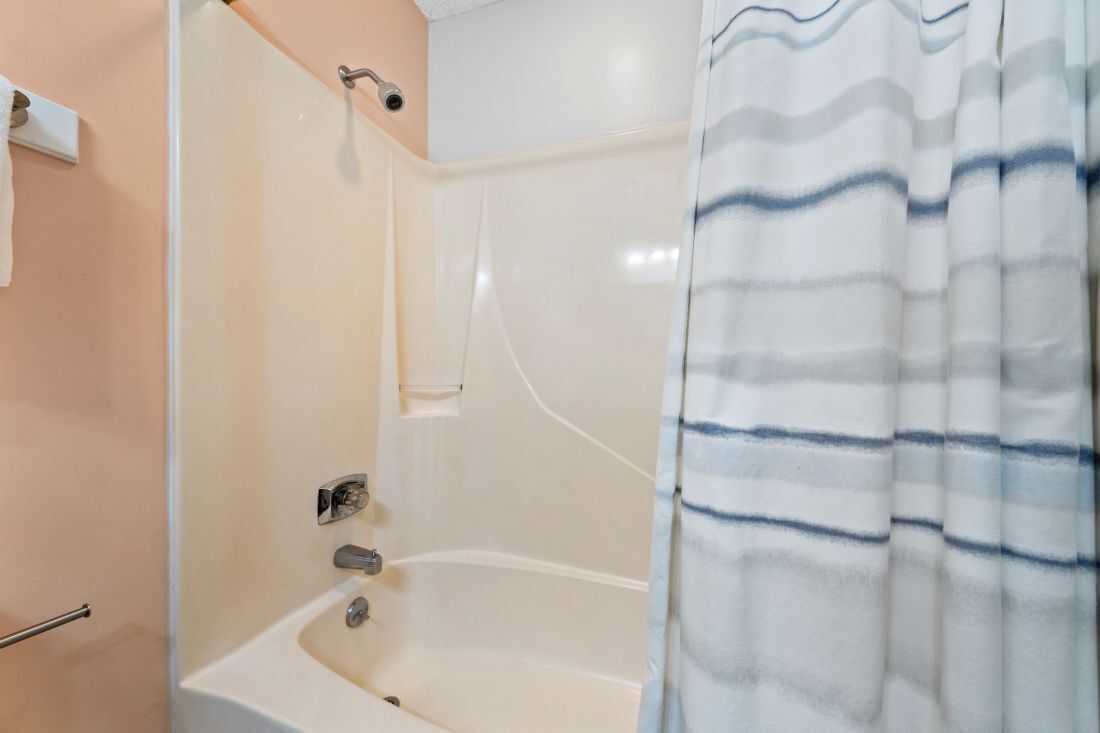 Un baño con bañera, toallero y cortina de ducha.