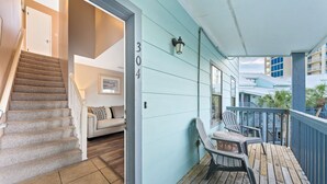 Terraza de madera con sillas, una escalera y una pared exterior azul claro con el número 304.