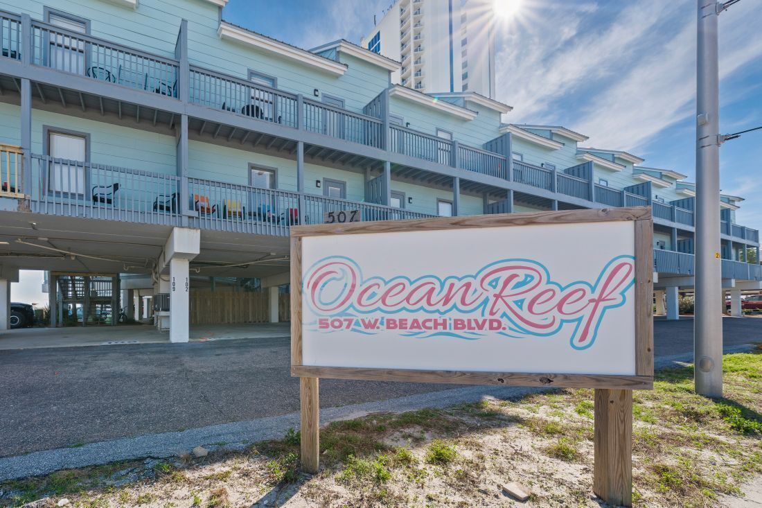 A sign for Ocean Reef at 507 W. Beach Blvd. with a multi-story building in the background.