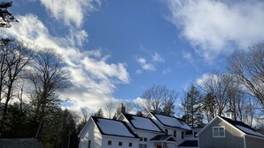 Een woongebied met meerdere huizen, een grote rots en sneeuwbedekte grond.