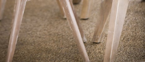 Une rangée de tables en bois, chacune accompagnée de chaises, et sur chaque table, une théière, une tasse et une soucoupe.