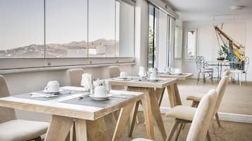 A modern dining area with large windows, wooden tables, and comfortable chairs.
