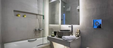 A modern bathroom with a bathtub, a glass-enclosed shower, a large mirror, and a toilet.
