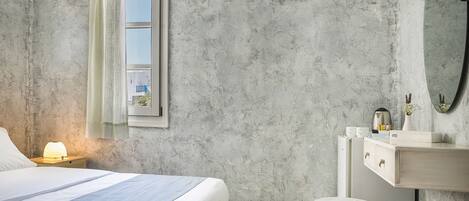 A bedroom with a bed, bedside table, nightstand, and a dresser with a mirror.