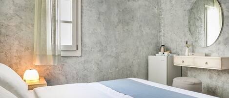 A bedroom with a bed, bedside table, lamp, dresser, mirror, and window.