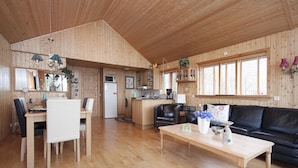 Un vaste espace de vie doté d’un plancher en bois, d’un canapé en cuir noir, d’une table basse en bois et d’un coin repas avec une table et des chaises.