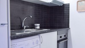 Una cocina compacta con lavadora, un lavabo y una estufa.