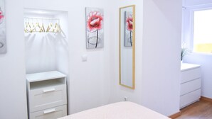 Un dormitorio con cama, armario, espejo y obras de arte en la pared.