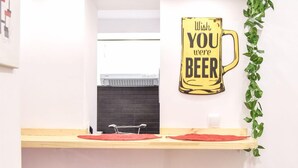 Una zona de bar con dos taburetes rojos, una barra de madera y un cartel en la pared que dice 