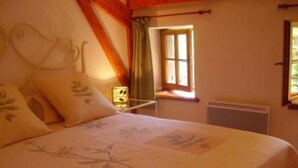 Ein Schlafzimmer mit Bett, Kissen, einem Nachttisch, einem Fenster und einer Heizung.