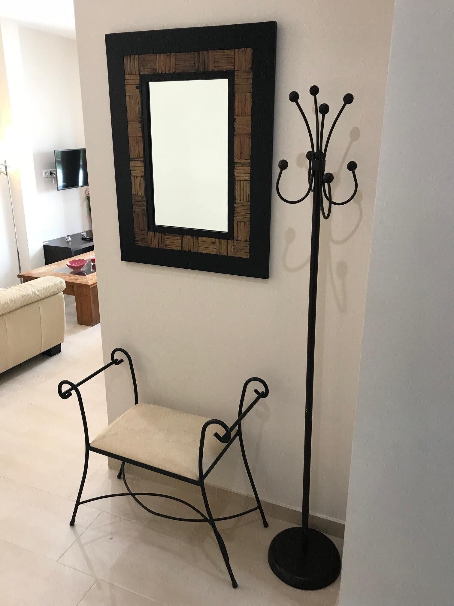 Une pièce comprenant un banc, un porte-manteau et un miroir encadré accroché au mur.