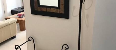 Une pièce comprenant un banc, un porte-manteau et un miroir encadré accroché au mur.