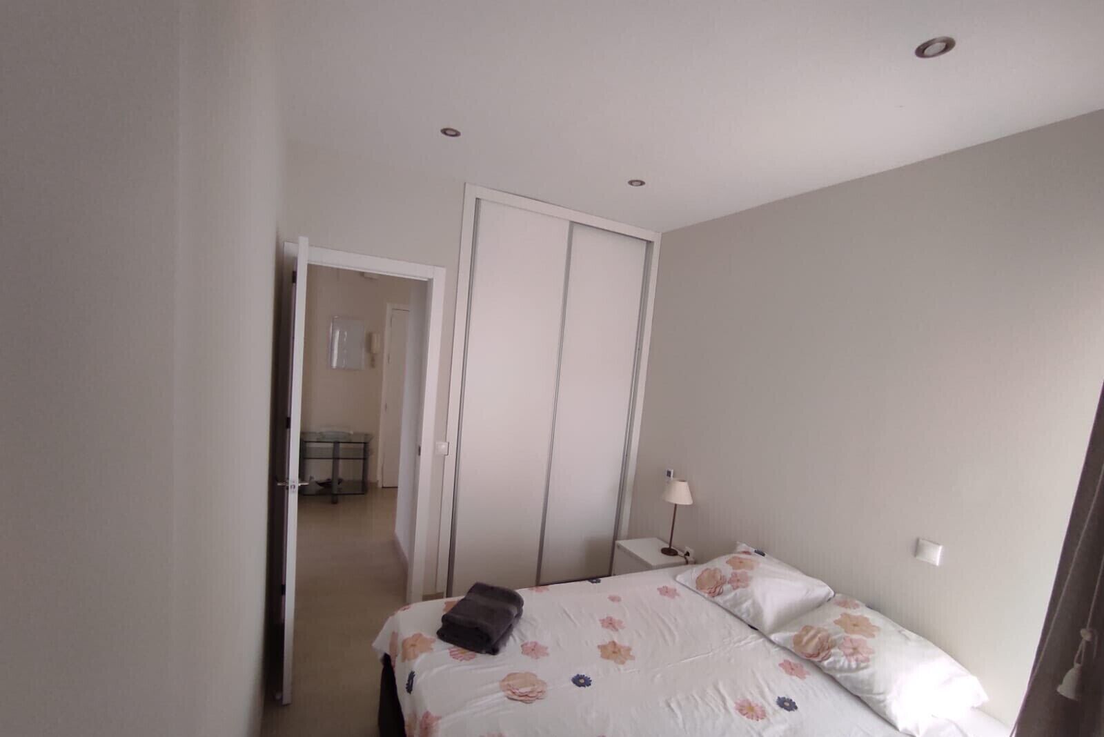 A bedroom with a bed, a nightstand, a lamp, and a wardrobe.