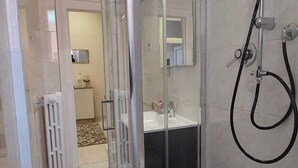 A modern bathroom with a glass-enclosed shower, a visible sink, and a radiator. - LA MAISON SR Cozy apartment in the center of town (Campobasso)