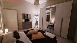 A modern bedroom with a bed, bedside lamps, a dresser, a chair, and a wardrobe. - LA MAISON SR Cozy apartment in the center of town (Campobasso)