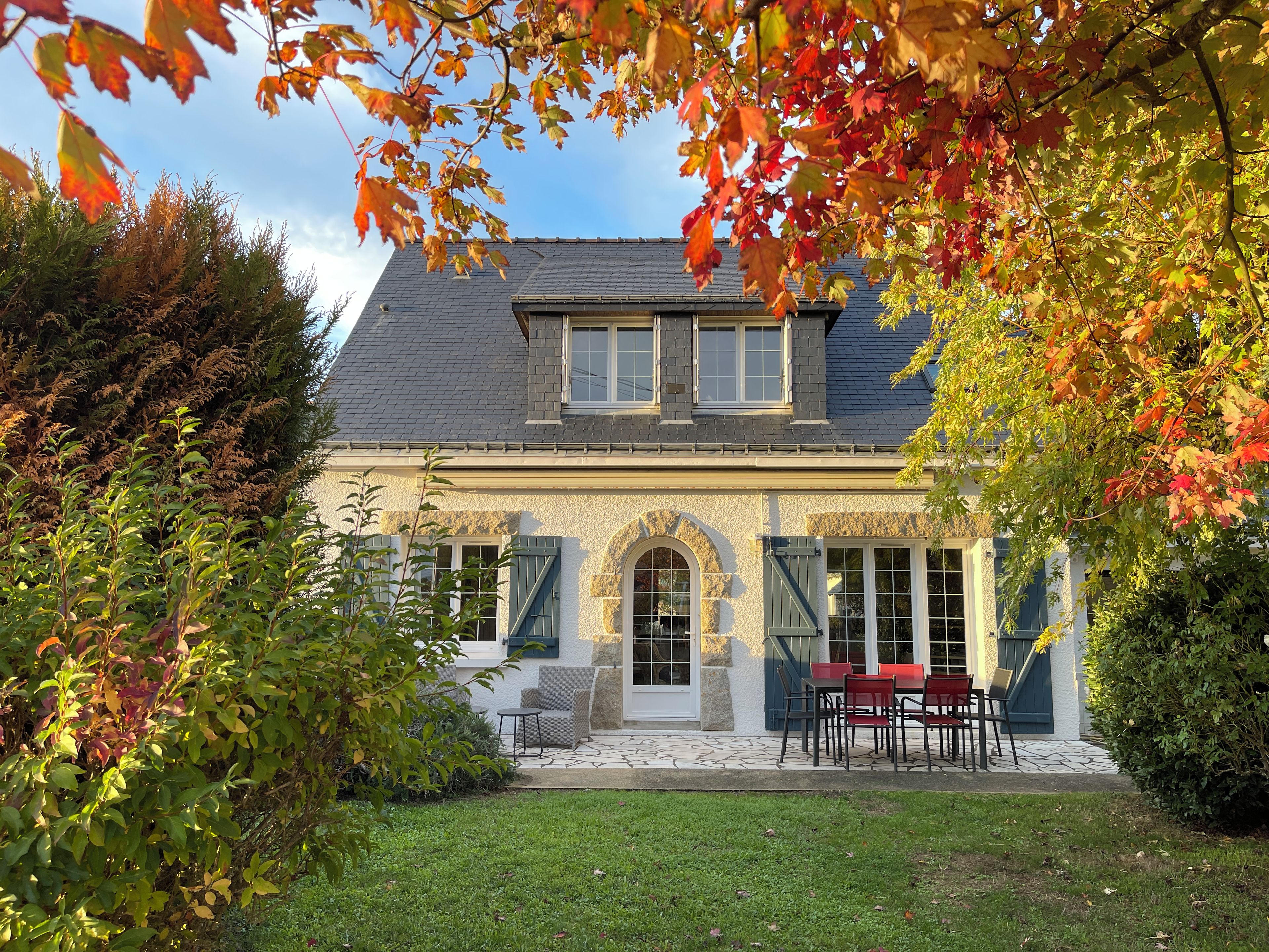 A house with a stone facade, a tiled roof, and a front porch with outdoor seating.