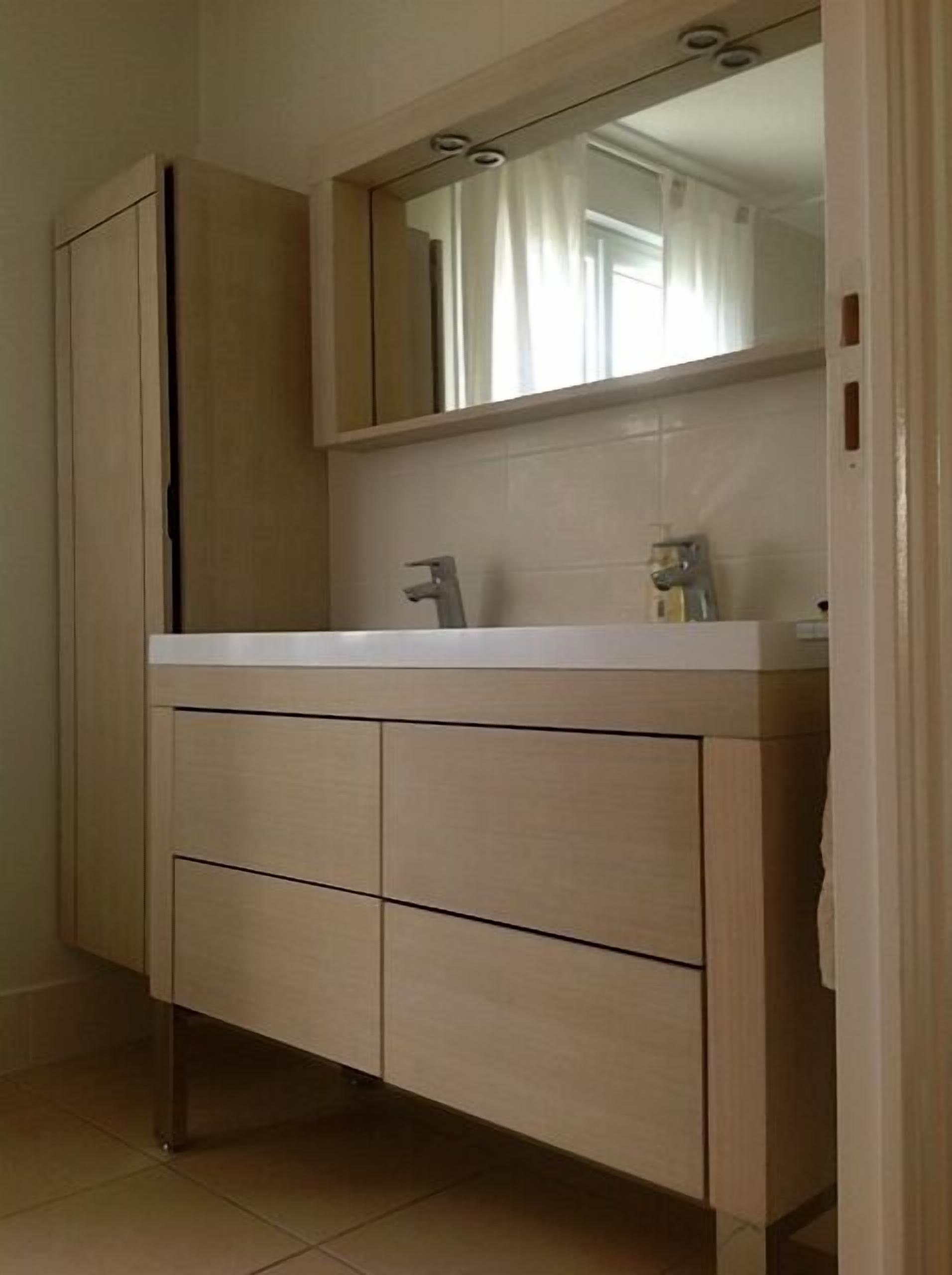 A bathroom with a large mirror, a sink, and a cabinet.