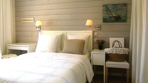 Un dormitorio ordenado con cama, dos mesitas de noche, una lámpara, un cuadro y una cesta de mimbre.