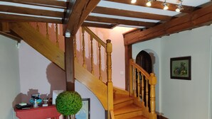 Una escalera de madera con una mesa roja y una planta verde a su lado.