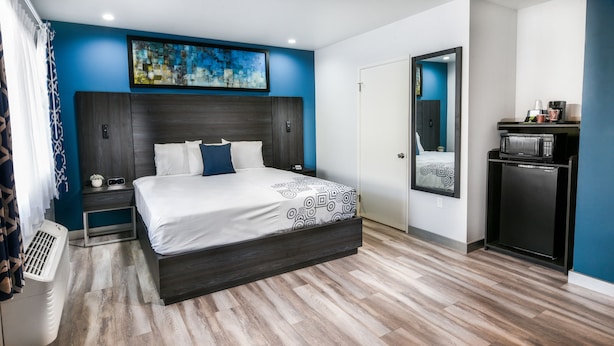 A modern hotel room with a large bed, a small desk, a microwave, and a coffee machine. - Parkside Inn Anaheim (Anaheim)
