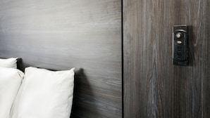 A bed with white linens and a wall-mounted electrical outlet with a switch. - Parkside Inn Anaheim (Anaheim)