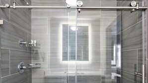 A modern shower with a glass door, chrome fixtures, and a rectangular mirror. - Parkside Inn Anaheim (Anaheim)
