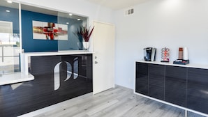 A reception area with a modern design, featuring a glass partition, a coffee machine, and a plant on the counter. - Parkside Inn Anaheim (Anaheim)