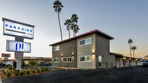 A modern motel with a sign for Parkside Inn, featuring a two-story building, palm trees, and a parking lot. - Parkside Inn Anaheim (Anaheim)
